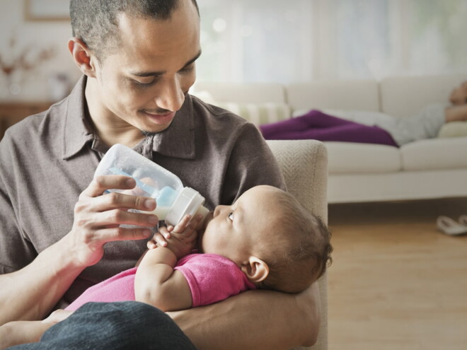 Baby girl drinking her bottle on daddy's lap